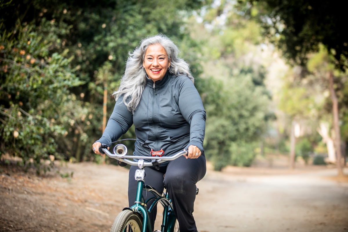 A woman smiles while riding a bike